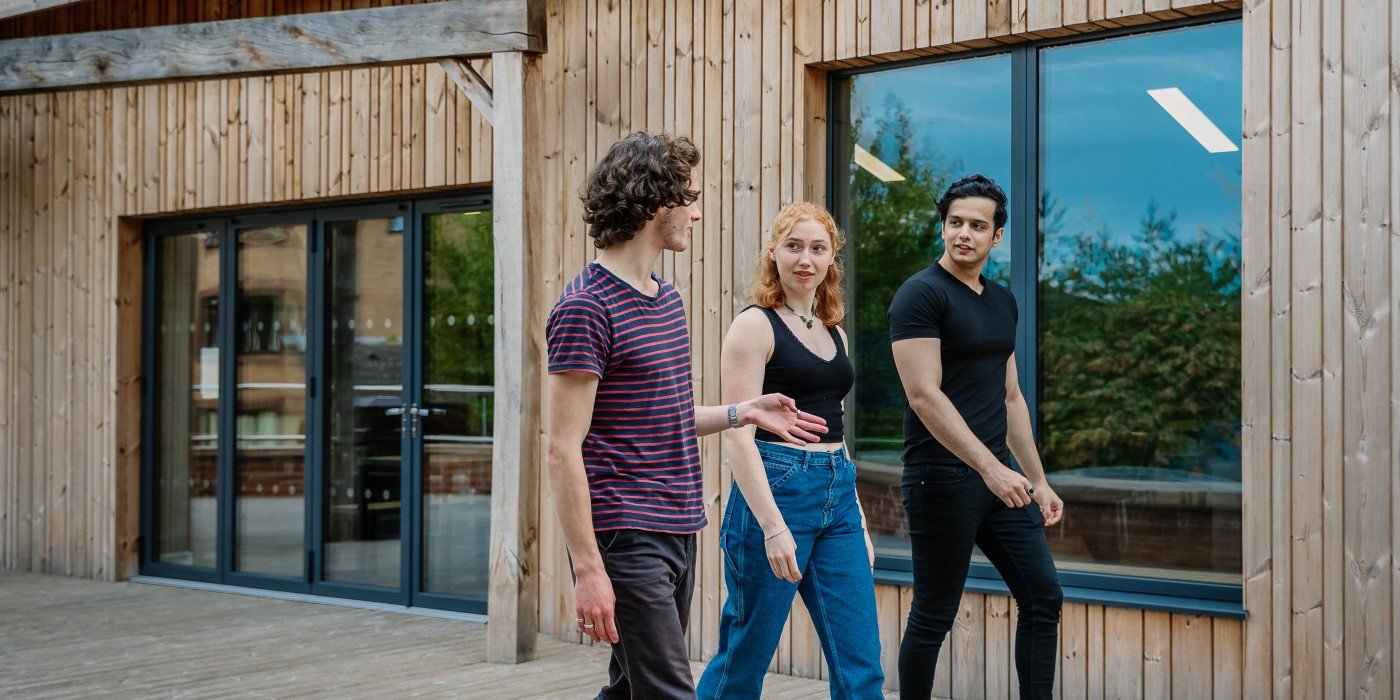Three students walking on the decking outside of the Montague Burton common room
